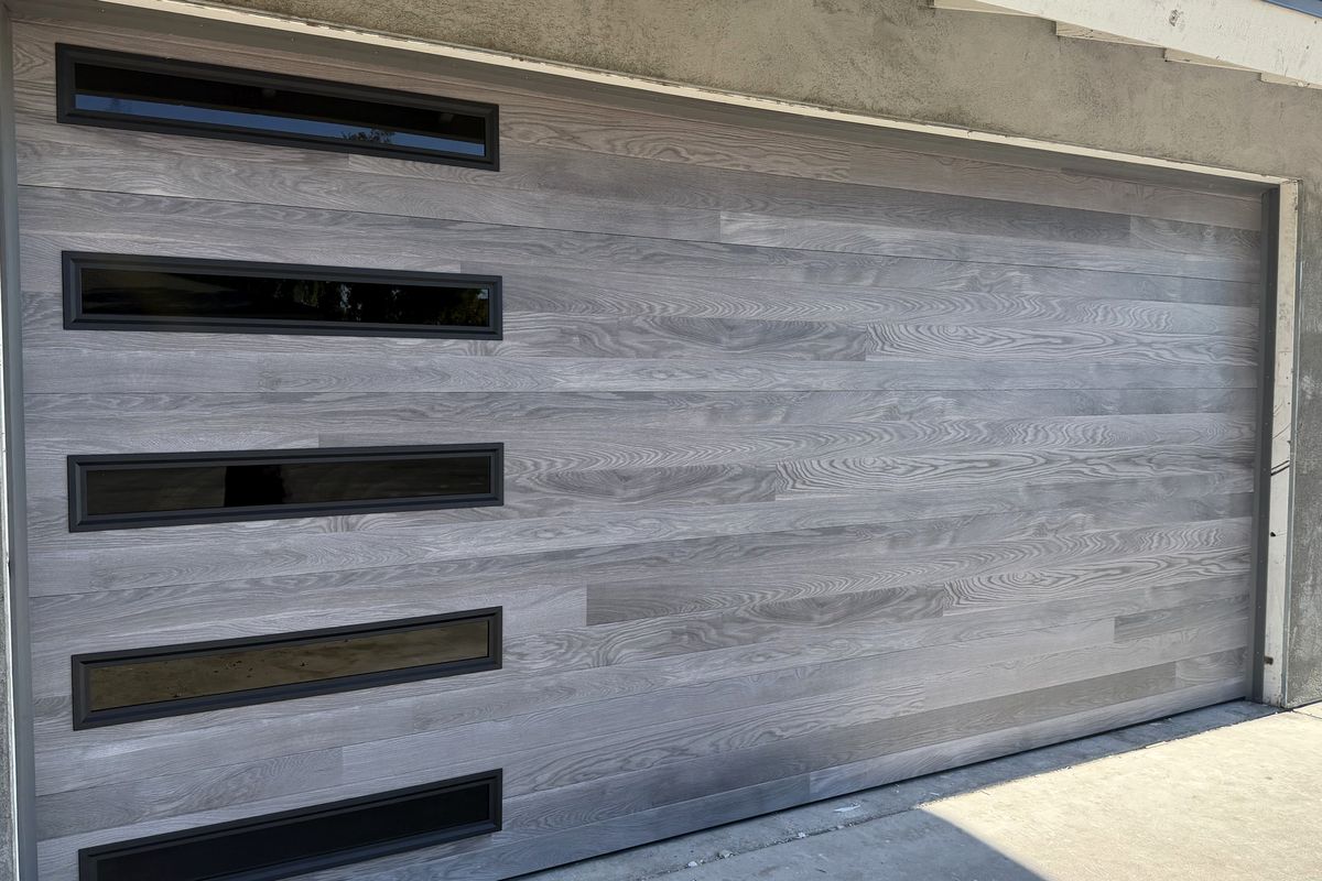 Modern grey woodgrain garage door with slim black windows